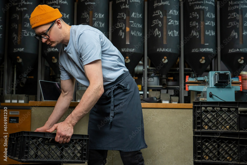 Caucasian man coffee shop worker gets new batch of coffee packages in boxes on roasting factory. Caucasian man coffee shop worker gets new batch of coffee packages in boxes on roasting factory.