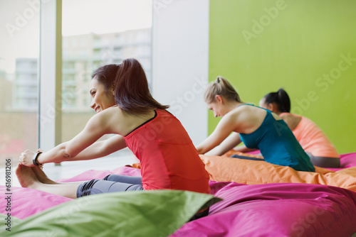 Φωτογραφία Women stretching legs in forward fold pose on cushions in restorative yoga gym s