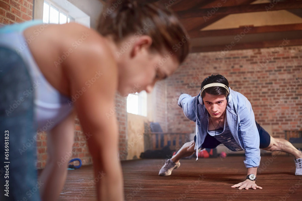 Young man with headphones doing one-arm push-ups in gym studio Young man with headphones doing one-arm push-ups in gym studio