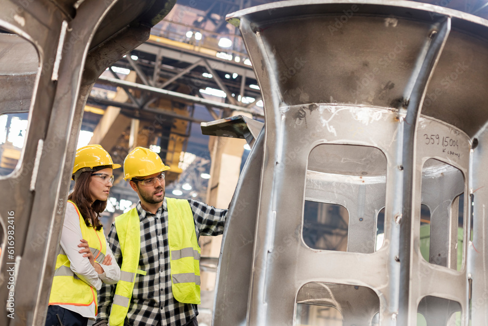 Steel workers examining part in factory Steel workers examining part in factory