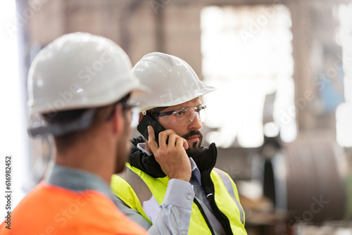 Steel workers talking on cell phone in factory photo