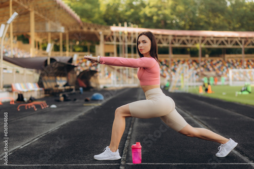 Young sportswoman doing warm up exercise on running track