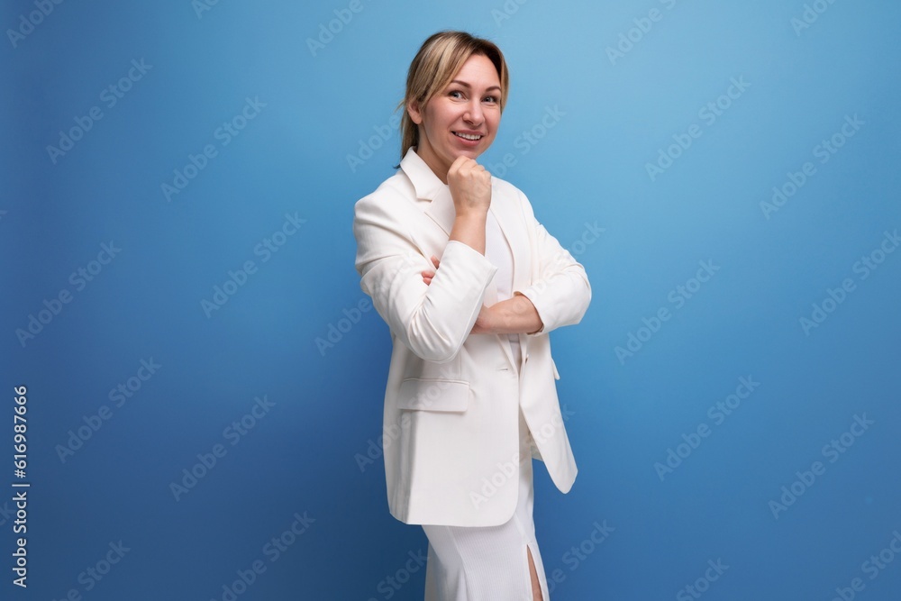 young confident pretty slim blond boss woman in an elegant jacket and dress on a blue background with copy space young confident pretty slim blond boss woman in an elegant jacket and dress on a blue background with copy space