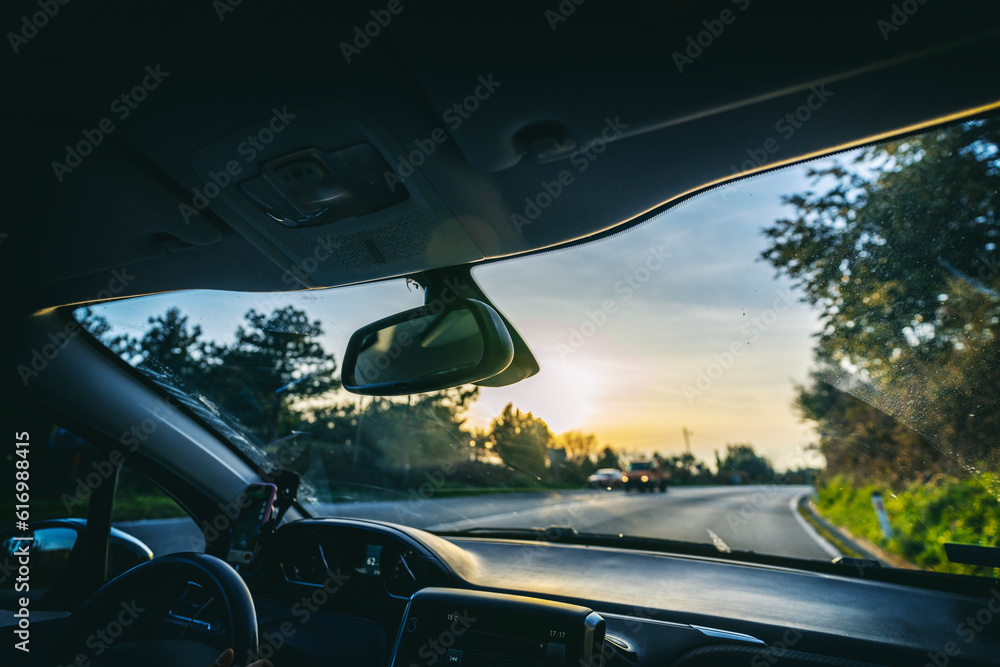 View from the car while driving on an asphalt road at sunset