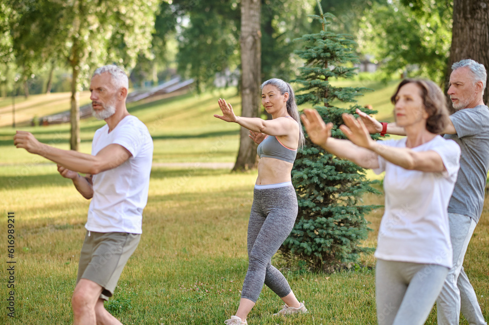A group of people practicing yoga in a park A group of people practicing yoga in a park