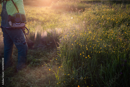 man moving the grass at sunset