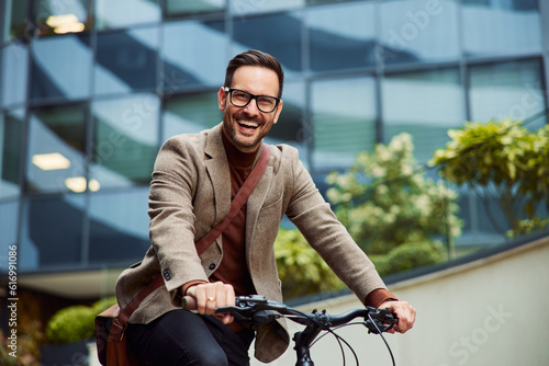 Portrait of a smiling businessman riding a bicycle in front of the company.
