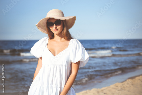 Happy smiling blonde woman is posing on the ocean beach with sunglasses and a hat © rogerphoto