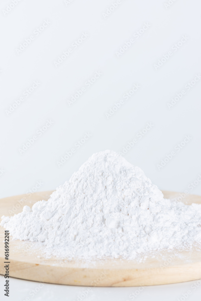 Pile of tapioca starch in the form of white powder on a wooden board.