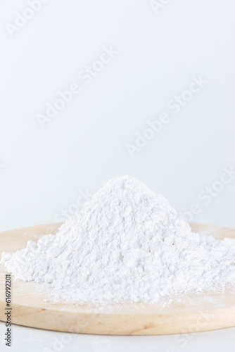 Pile of tapioca starch in the form of white powder on a wooden board.