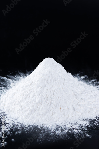 Tapioca starch on a black background, dry cassava root. Vertical orientation. photo