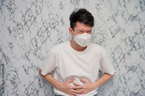 Man puts on a face mask tummyache isolated on White background,pandemic and social distancing concept.Covid-19 photo
