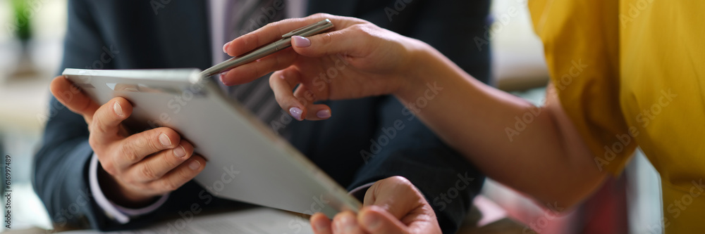 Business colleagues studying information on digital tablet while meeting in office closeup. Marketing concept