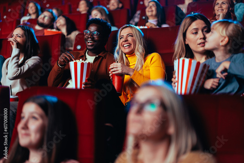 Multiracial couple watching fun movie in theater.
