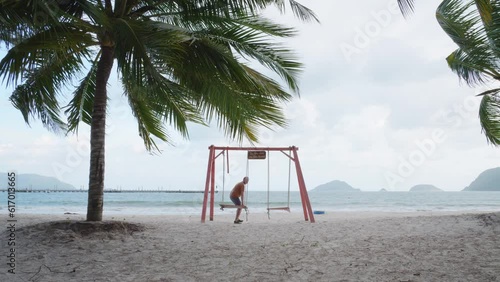 Person Sit On A Swing In Front Of Bai Tam An Hai Beach In Con Dao Island, Vietnam. Slow Motion photo