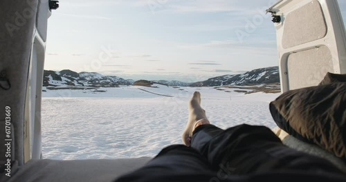 Point of view of crossed feet inside campervan in snowy Aurland mountain sunset photo