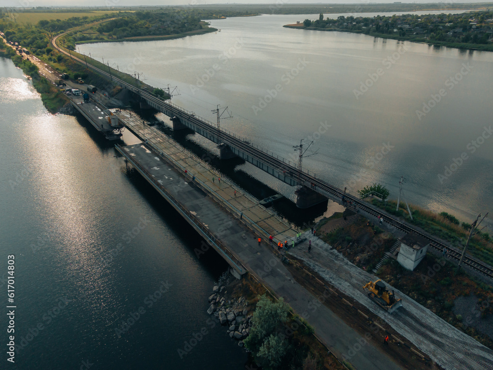 Pontoon bridge of the Ukrainian army. Installation of a temporary crossing near the destroyed bridge. Soldiers collect pontoon ferry. Top view from a drone. Nikopol, UKRAINE – May 26, 2020