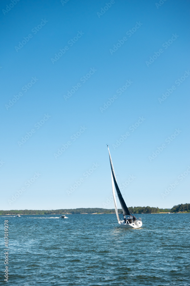 Naklejka premium Sailboat with black sails on adventurous sailing holiday in picturesque archipelago landscape by the coast in Sweden, Scandinavia