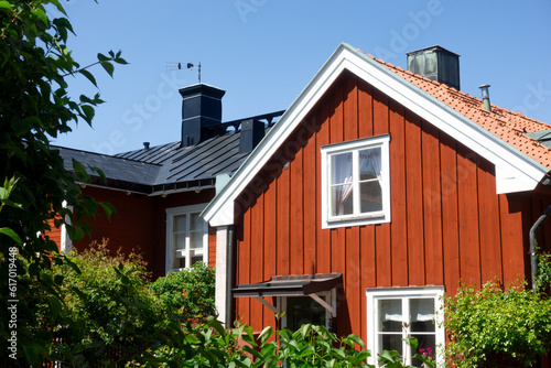 Gable of a traditional vintage falu red house with white corners and trims in rural Swedish Stockholm archipelago with lush green garden in summer with clear blue sky with no clouds photo