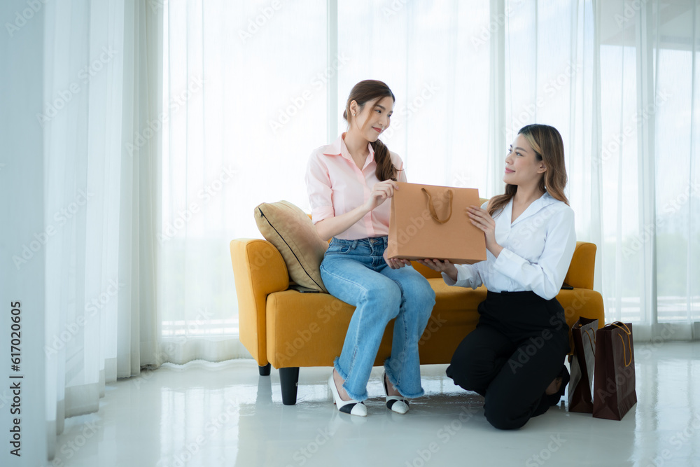 The receptionist delivers the goods that the customer has already purchased to Asian women on the sofa with shopping bags The receptionist delivers the goods that the customer has already purchased to Asian women on the sofa with shopping bags