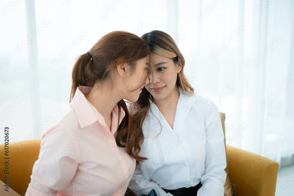 Happy LGBT couple hugging and holding bouquet on sofa in living room. Happy LGBT couple hugging and holding bouquet on sofa in living room.