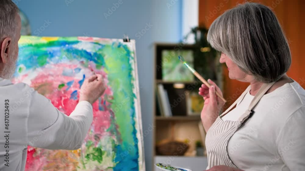 retirement hobby, cheerful male and female pensioners learn modern art and paint creative picture with paints and brushes at home retirement hobby, cheerful male and female pensioners learn modern art and paint creative picture with paints and brushes at home