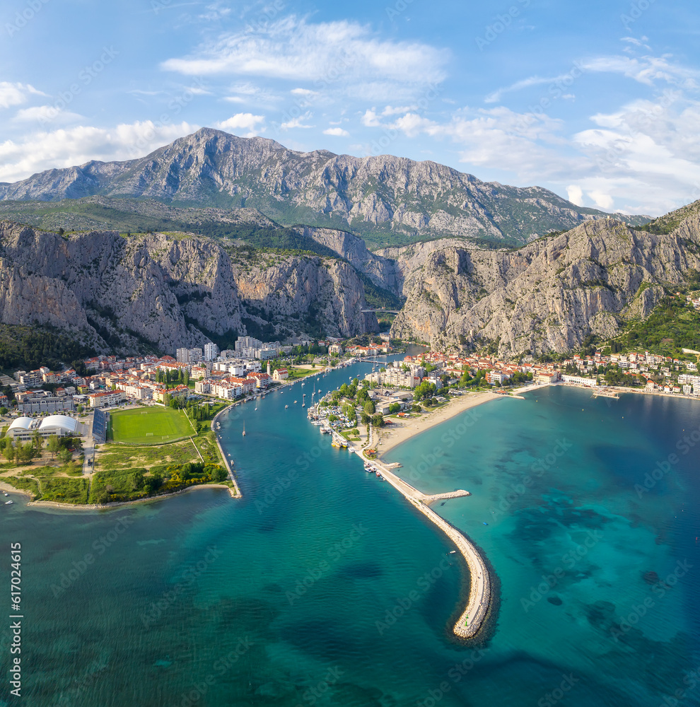 Amazing panoramic view of the picturesque town of Omish in Croatia, the cliffs, the old houses with red roofs, the historic buildings and the river flowing into the turquoise Adriatic Sea