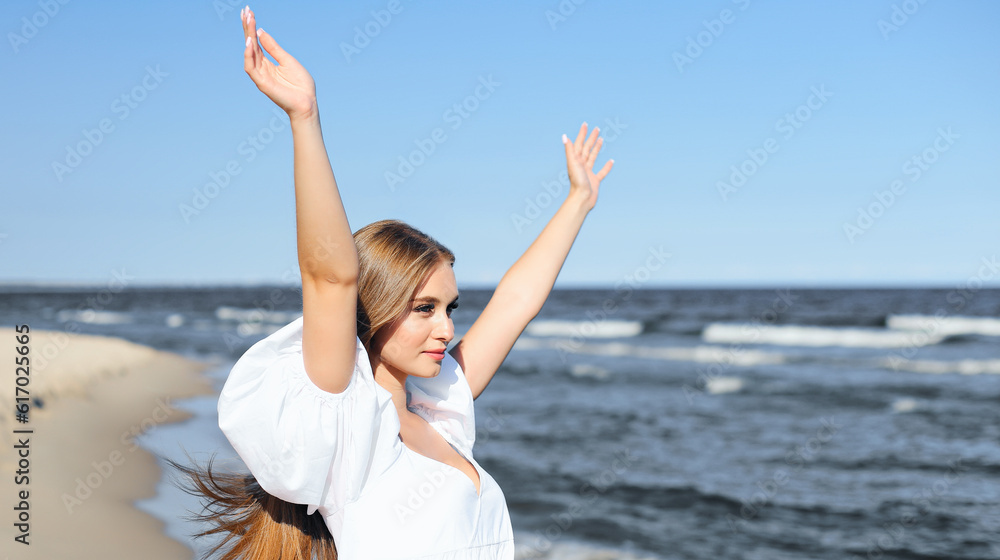 Happy, beautiful woman on the ocean beach standing in a white summer dress, raising hands Happy, beautiful woman on the ocean beach standing in a white summer dress, raising hands