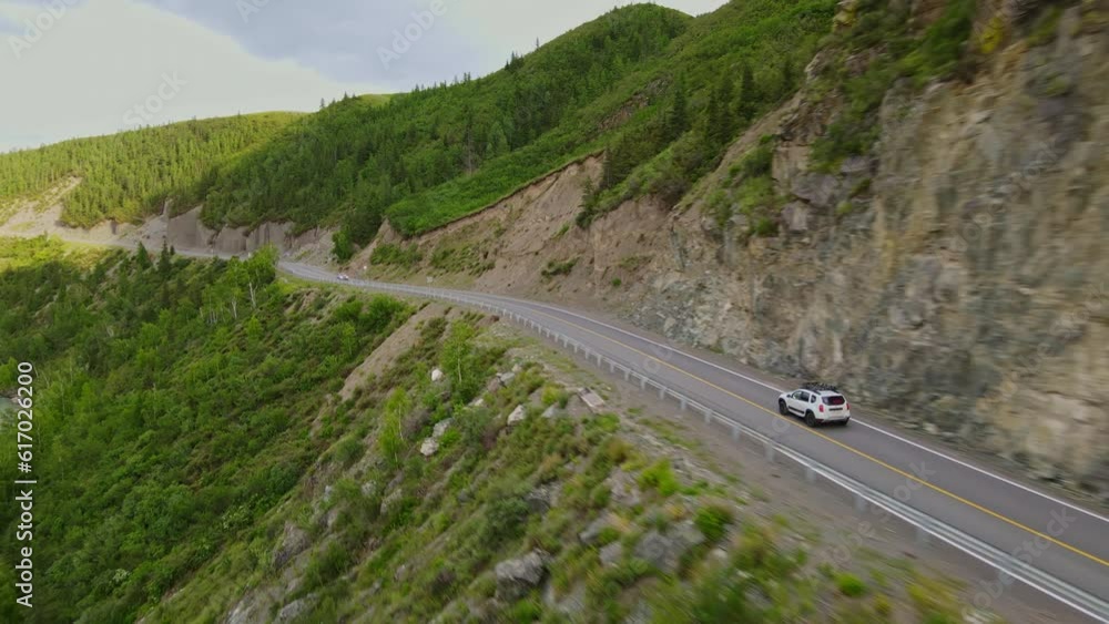 A car is driving along a mountain road near the forest A car is driving along a mountain road near the forest