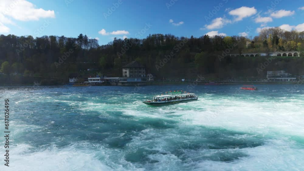 Boats for tourists float near the Rhine Falls with spray against the old town in Switzerland Boats for tourists float near the Rhine Falls with spray against the old town in Switzerland