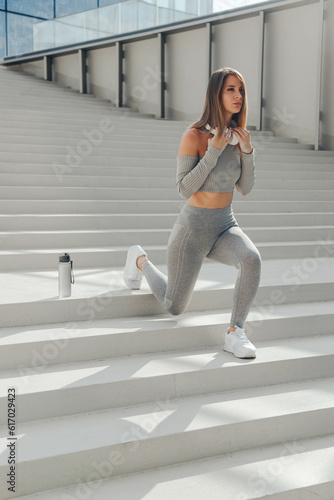 Sporty european woman stretching legs on stairs before running outdoors
