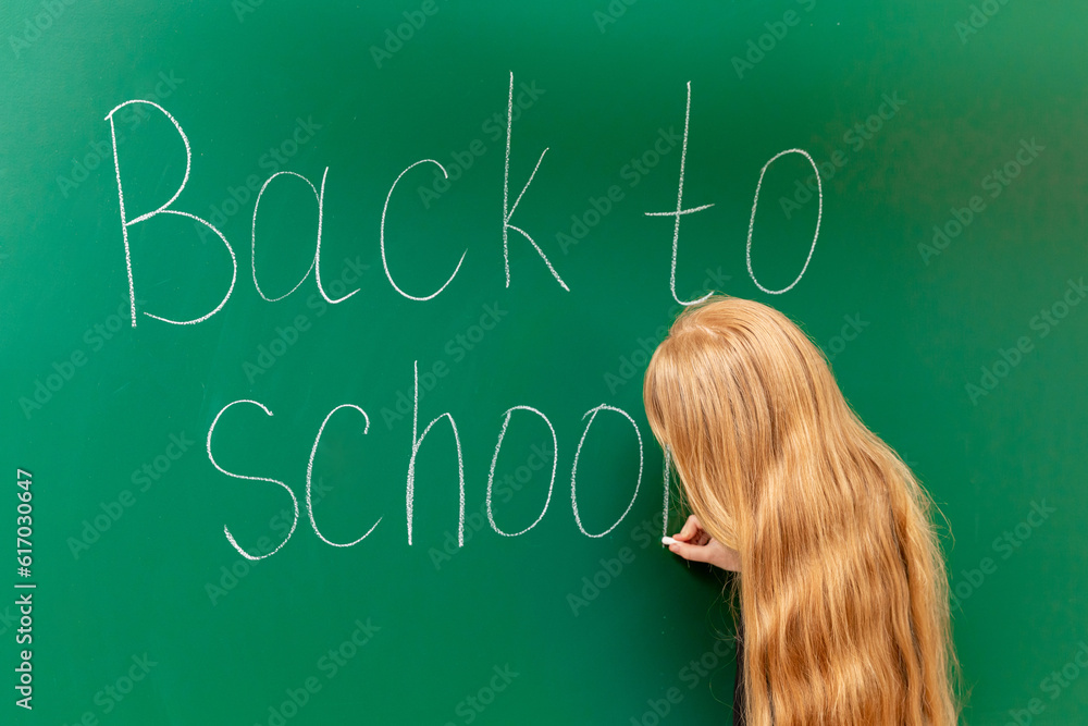 Schoolgirl writing on a blackboard.Back to School. Education. Student near Blackboard. School Life. Schoolgirl writing on a blackboard.Back to School. Education. Student near Blackboard. School Life.