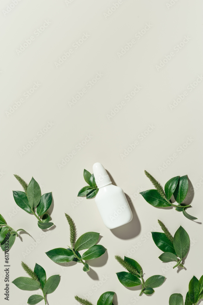 Seasonal allergy concept, spring young branches tree with new green leaves and catkins and white nasal spray on beige background, minimal creative top view, aesthetic flat lay. Healthy lifestyle