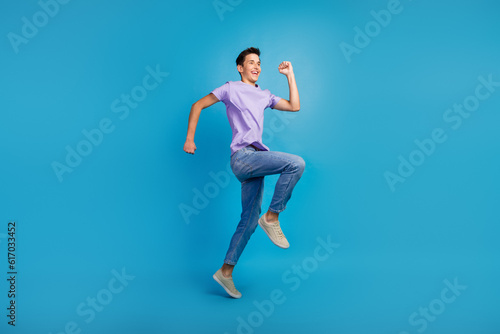 Fototapeta Naklejka Na Ścianę i Meble -  Full length portrait of excited young man in t-shirt jumping success fast going over blue color background