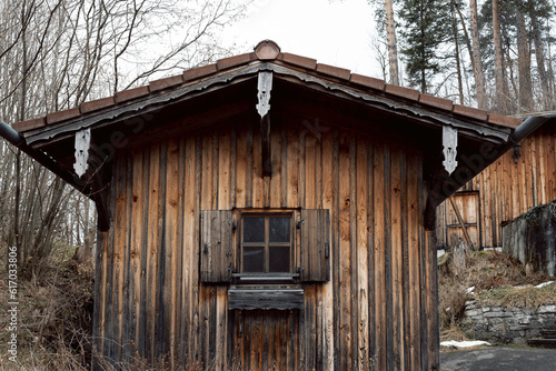 An old wooden house stands on a slope in the middle of nature in the nearby environment of the city of Füssen am RA