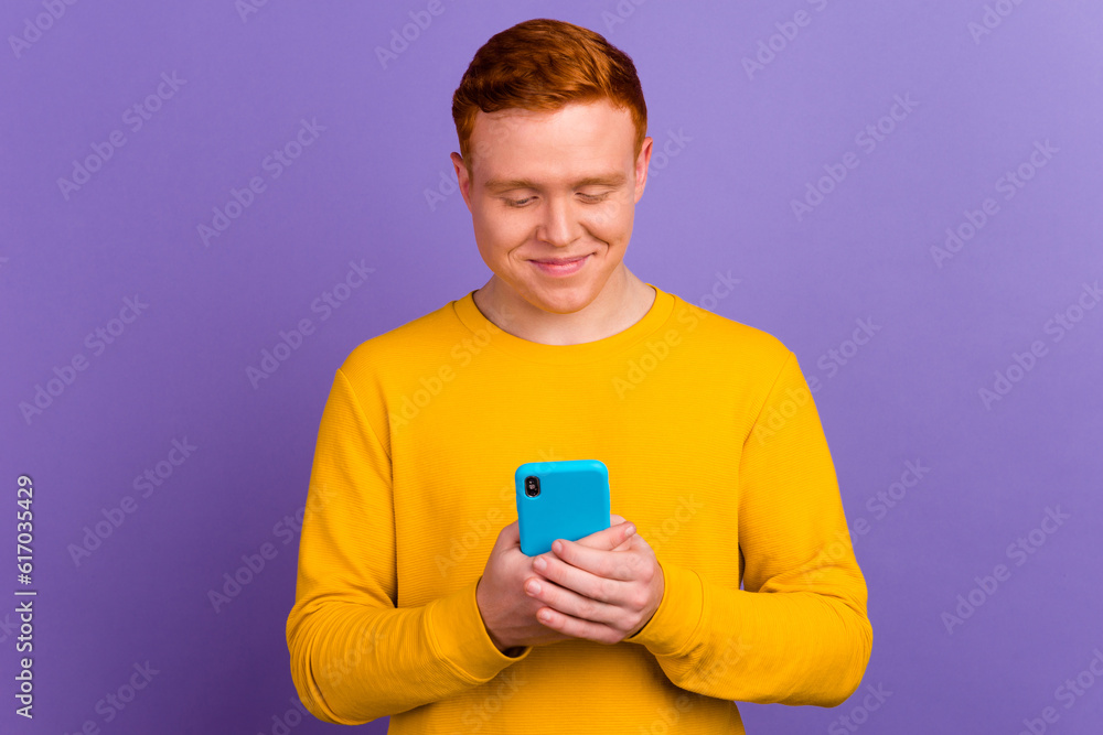 Happy young man using smart phone cellphone for calls social media mobile app isolated in violet background Happy young man using smart phone cellphone for calls social media mobile app isolated in violet background