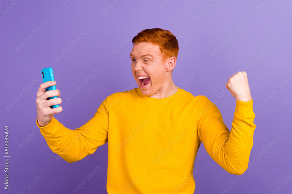 Happy caucasian crazy young man using smart phone for calls social media application online isolated in violet background Happy caucasian crazy young man using smart phone for calls social media application online isolated in violet background