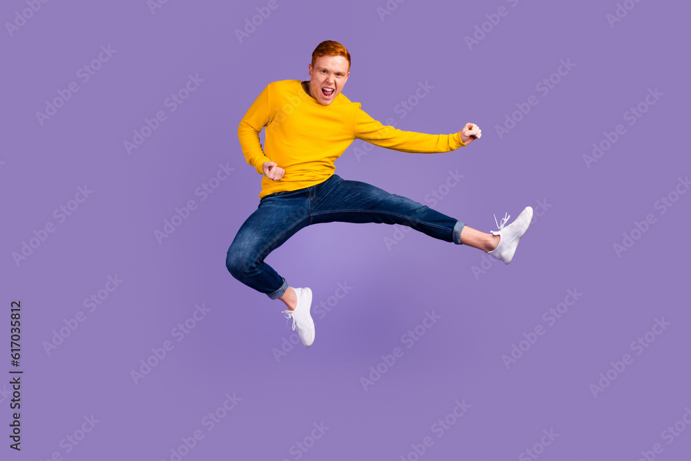 Full length portrait of excited young man jumping while celebrating success isolated over violet color background Full length portrait of excited young man jumping while celebrating success isolated over violet color background
