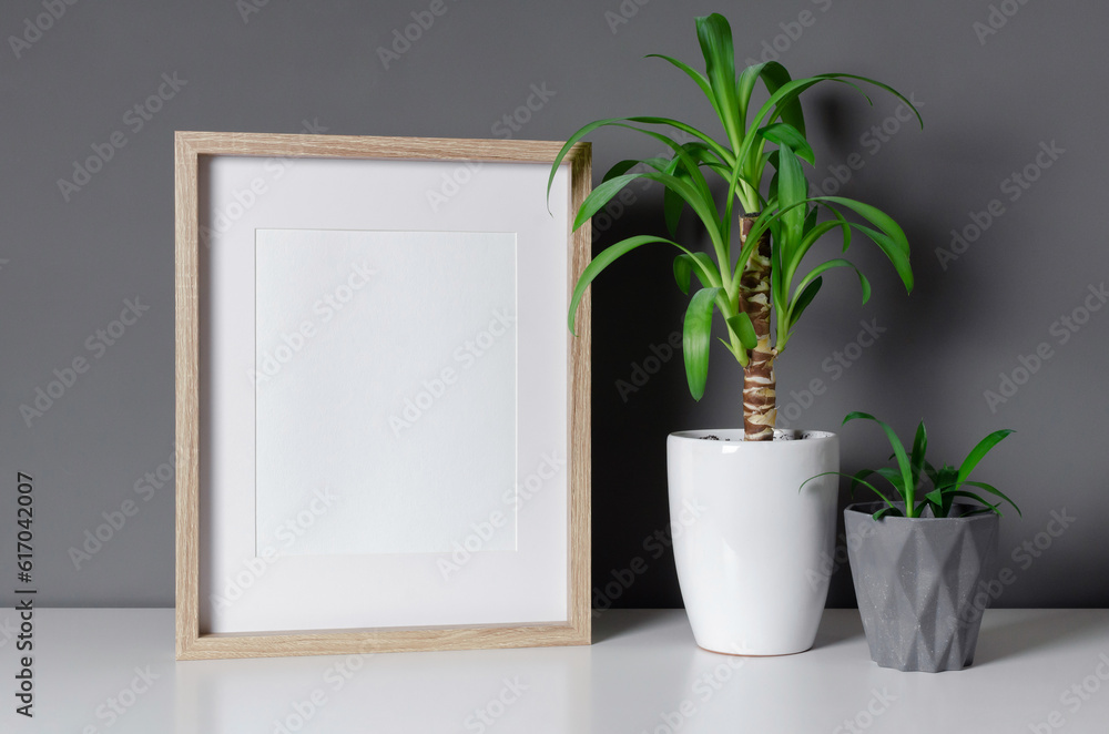 Vertical wooden frame mockup with green home plants, blank frame with copy space Vertical wooden frame mockup with green home plants, blank frame with copy space