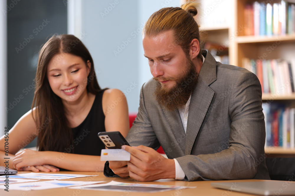 A Couple businessman hold credit card and mobile online shopping. Businessman shopping online with credit card using smart phone at office A Couple businessman hold credit card and mobile online shopping. Businessman shopping online with credit card using smart phone at office