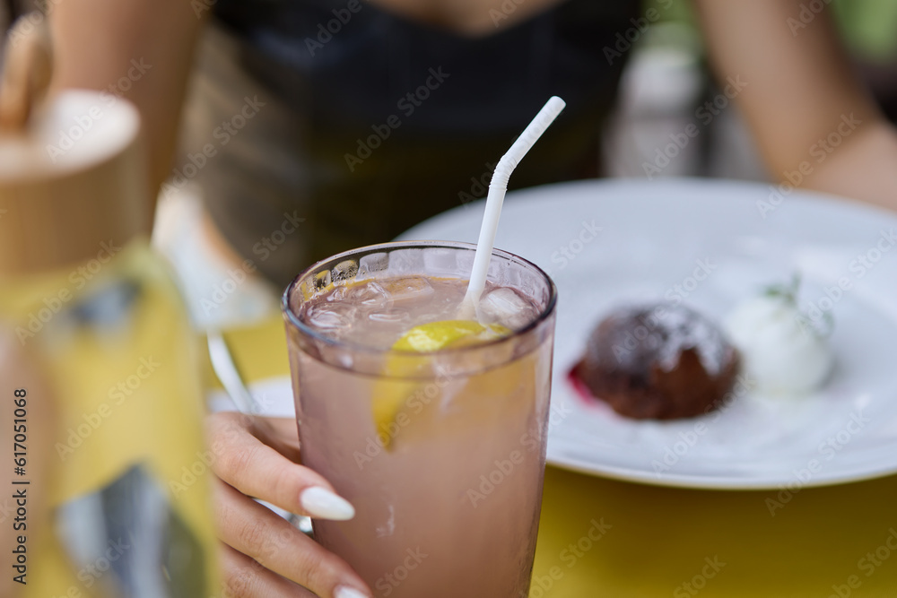 Young woman drinking fresh summer cocktail in a restaurant. Unrecognizable female person enjoying refreshing long drink and sweet dessert food for lunch in a cafe Young woman drinking fresh summer cocktail in a restaurant. Unrecognizable female person enjoying refreshing long drink and sweet dessert food for lunch in a cafe