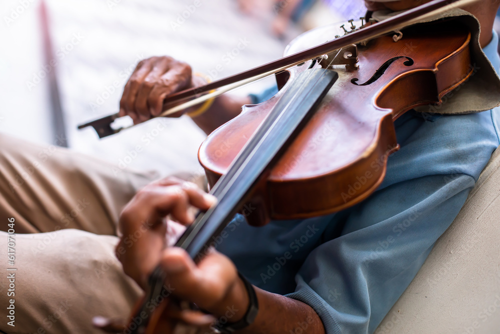 Selective focus to the violin with an old musician is playing it. Street musician in Bangkok. Selective focus to the violin with an old musician is playing it. Street musician in Bangkok.