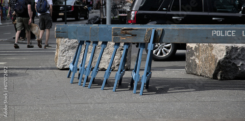 police barricades stacked on a sidewalk next to an intersection crosswalk (car and people passing) new york city, nyc (parade, protest, street fair, festival) do not cross blue nypd photo