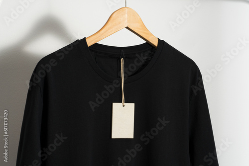 Obraz na płótnie Black t-shirt with blank price tag on wooden hanger