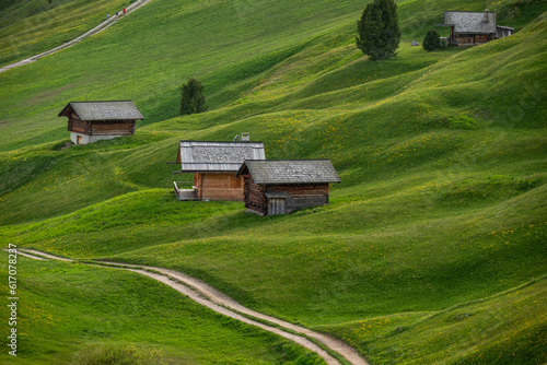 Wooden huts on the green hillside of the Seceda Mountain in the Dolomites, Italy 