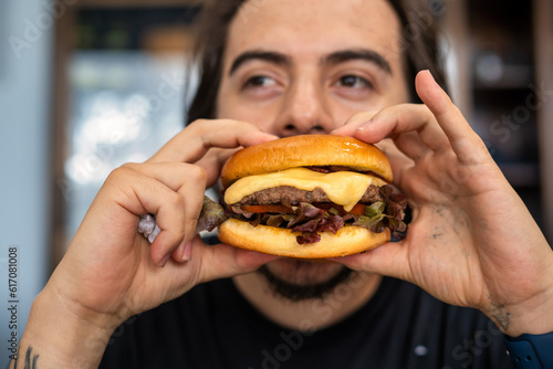 Man Holding Juicy Burger with Both Hands, Ready to Take a Bite - Close-Up