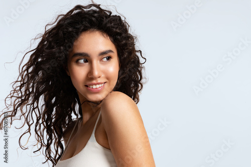 Fotografie Beautiful young woman with natural makeup , and shiny curly hair on a blue backg