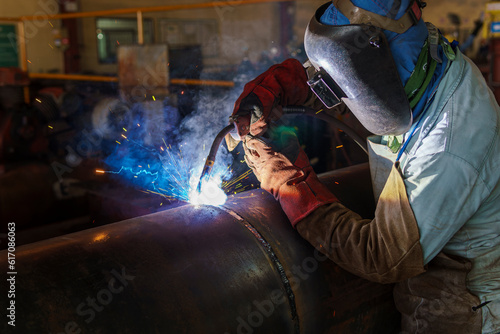 Welder is welding added joint a pipe carbon for steel structure work with process Flux Cored Arc Welding(FCAW) and dressed properly with personal protective equipment(PPE) for safety.
