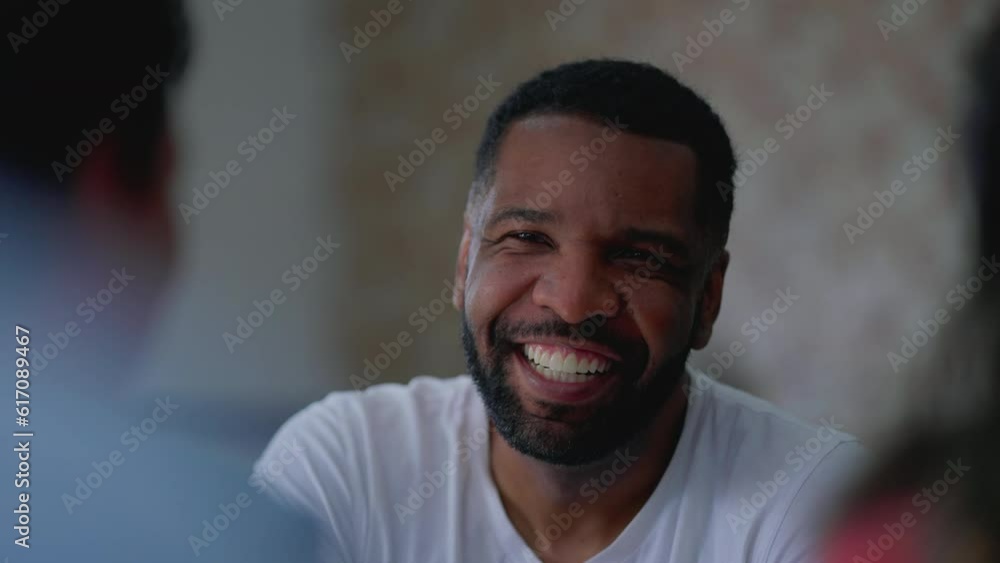Close-up face of a friendly charismatic black man conversing and laughing with friends Close-up face of a friendly charismatic black man conversing and laughing with friends
