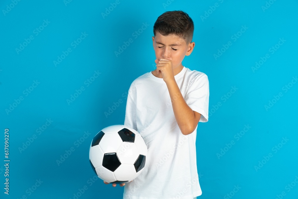 Little hispanic boy wearing white Tshirt holding a football ball